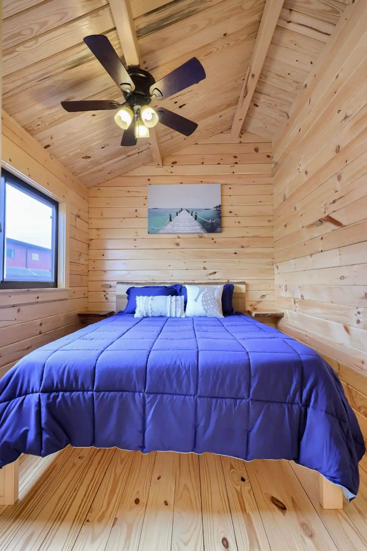 blue blanket on bed in small cabin room with ceiling fan