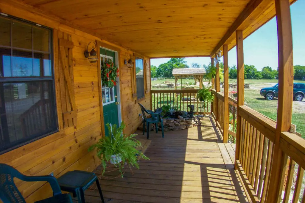 Wooden porch with potted plants and fountain.