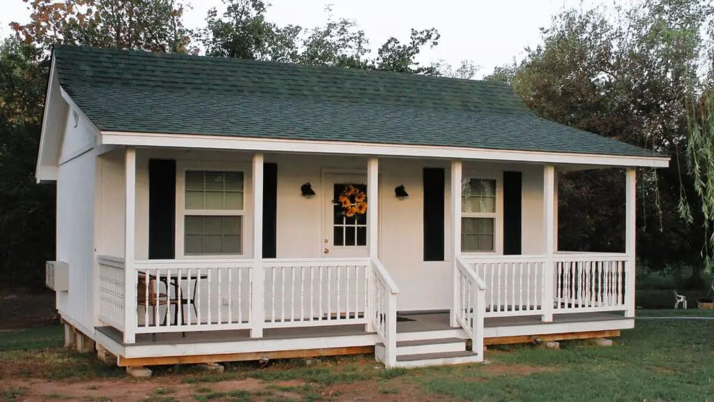 White cottage with porch and sunflower wreath.